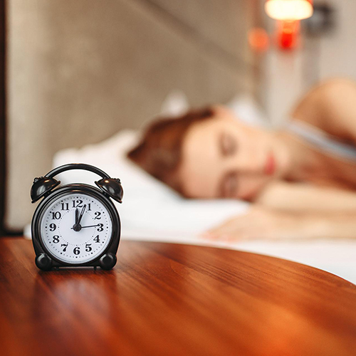 Mujer dormida y un reloj despertador